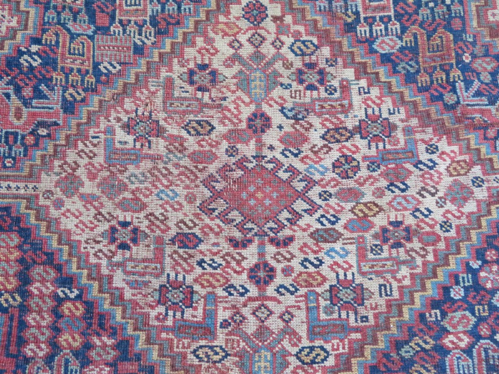 An antique Khamseh nomadic wool rug featuring complex geometric medallions, bird motifs, and multi-layered borders in terracotta, navy blue, and cream. View V