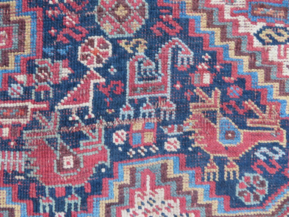 An antique Khamseh nomadic wool rug featuring complex geometric medallions, bird motifs, and multi-layered borders in terracotta, navy blue, and cream. View IX