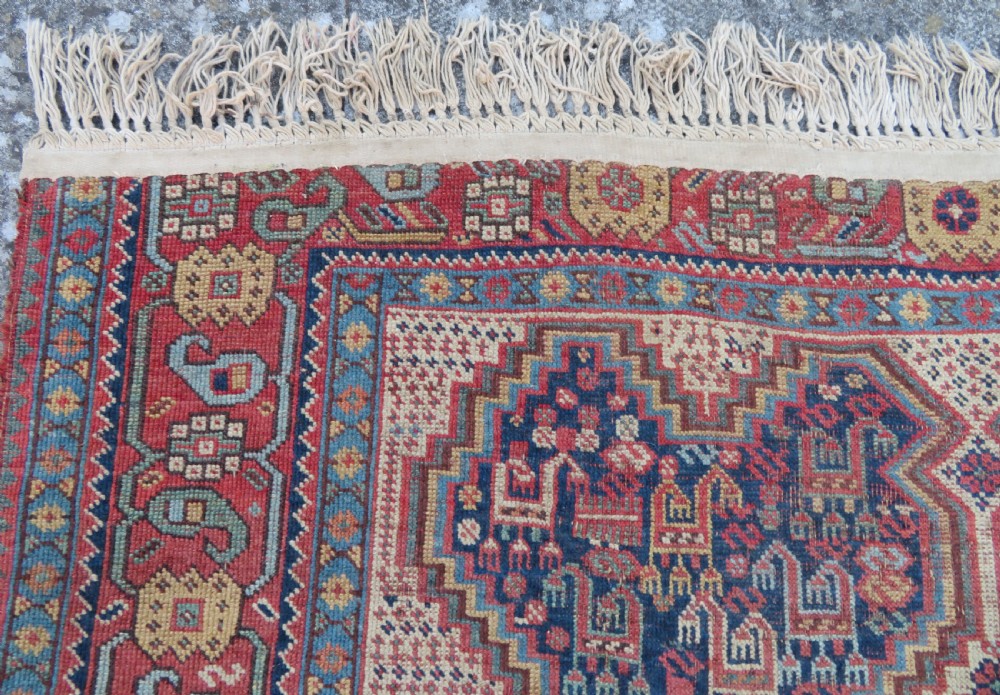 An antique Khamseh nomadic wool rug featuring complex geometric medallions, bird motifs, and multi-layered borders in terracotta, navy blue, and cream. View XIII