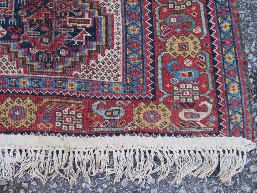 An antique Khamseh nomadic wool rug featuring complex geometric medallions, bird motifs, and multi-layered borders in terracotta, navy blue, and cream. View XVI
