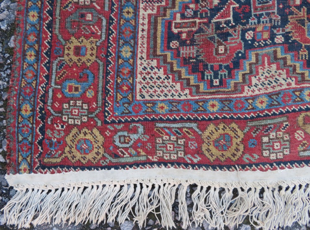 An antique Khamseh nomadic wool rug featuring complex geometric medallions, bird motifs, and multi-layered borders in terracotta, navy blue, and cream. View XVII