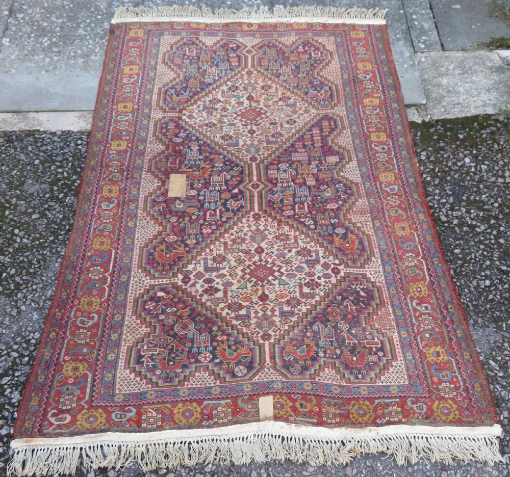 An antique Khamseh nomadic wool rug featuring complex geometric medallions, bird motifs, and multi-layered borders in terracotta, navy blue, and cream. View XX