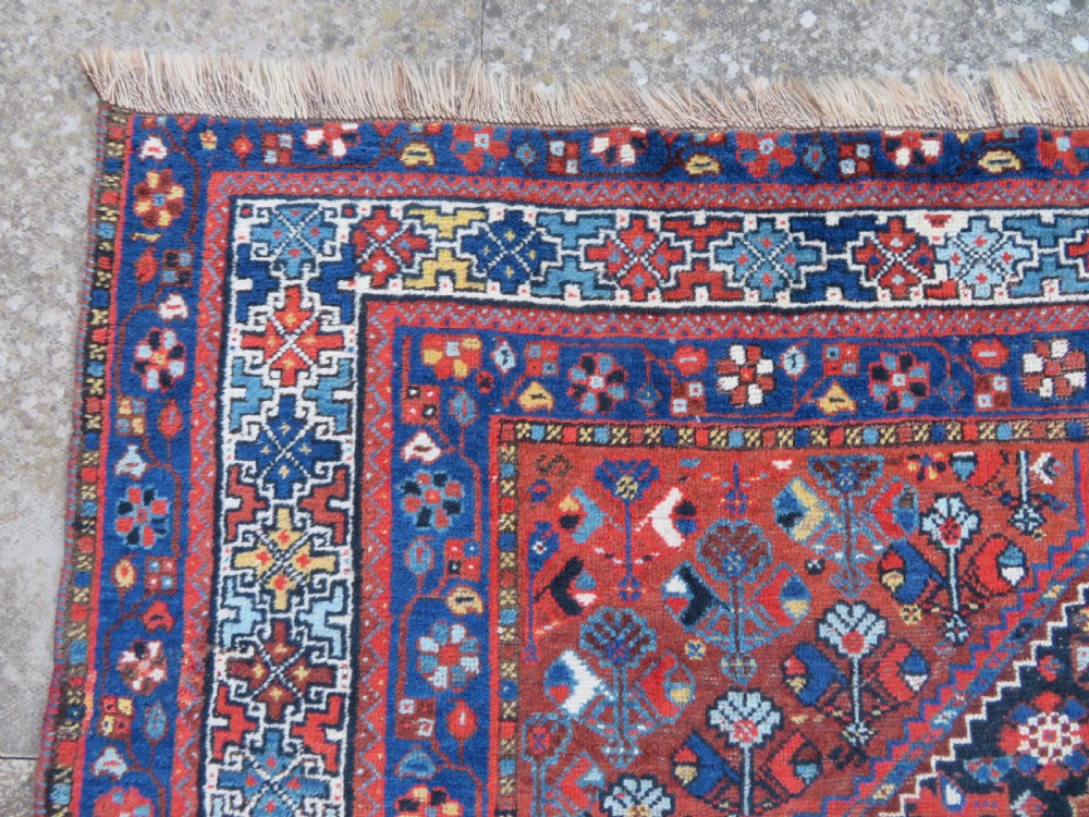 An antique Persian Khamseh wool carpet featuring a dark navy blue field with three stacked diamond medallions and geometric borders in terracotta red and ivory. View XII