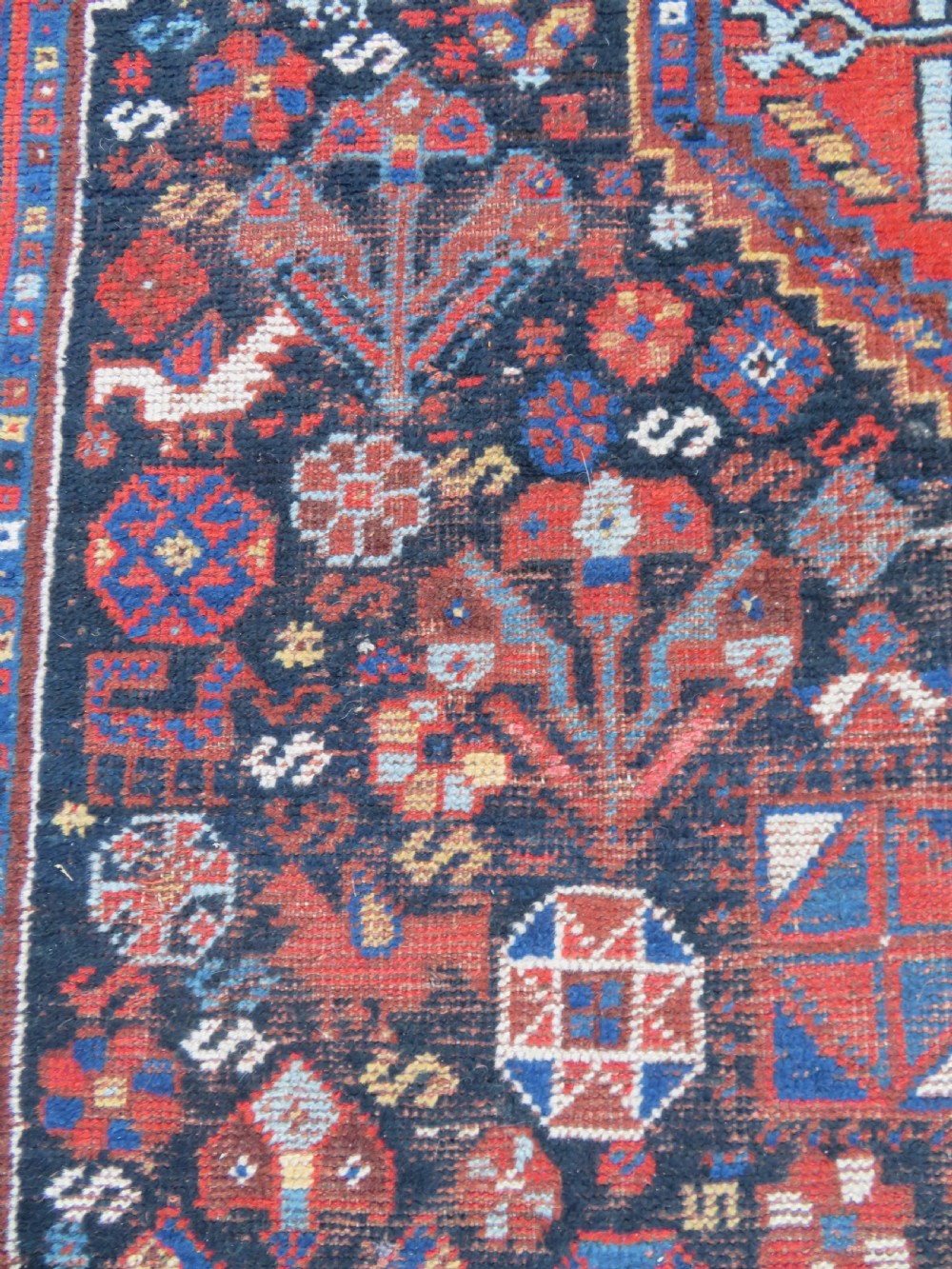 An antique Persian Khamseh wool carpet featuring a dark navy blue field with three stacked diamond medallions and geometric borders in terracotta red and ivory. View XIII