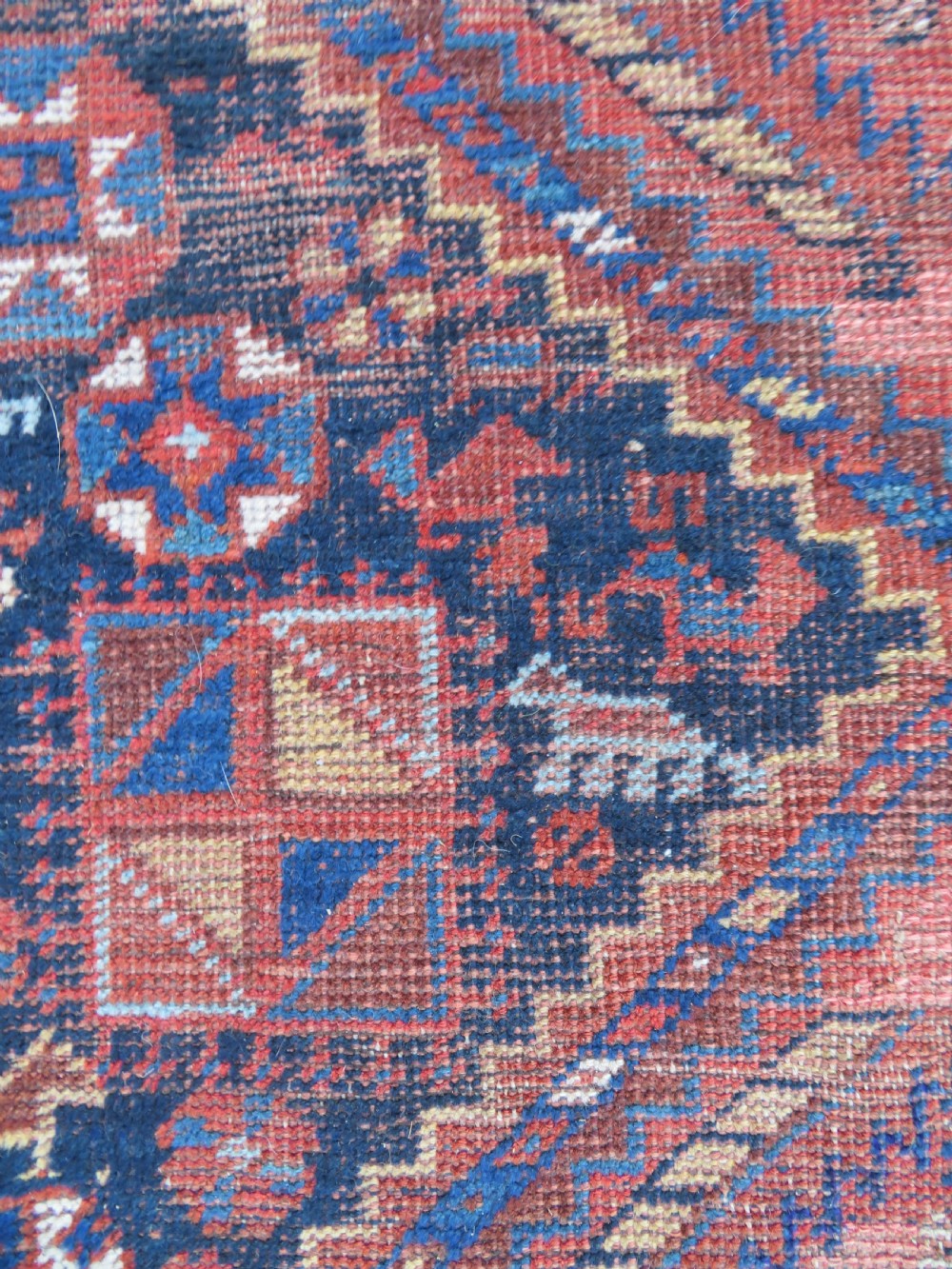 An antique Persian Khamseh wool carpet featuring a dark navy blue field with three stacked diamond medallions and geometric borders in terracotta red and ivory. View XIV
