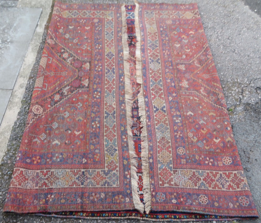 An antique Persian Khamseh wool carpet featuring a dark navy blue field with three stacked diamond medallions and geometric borders in terracotta red and ivory. View XXV
