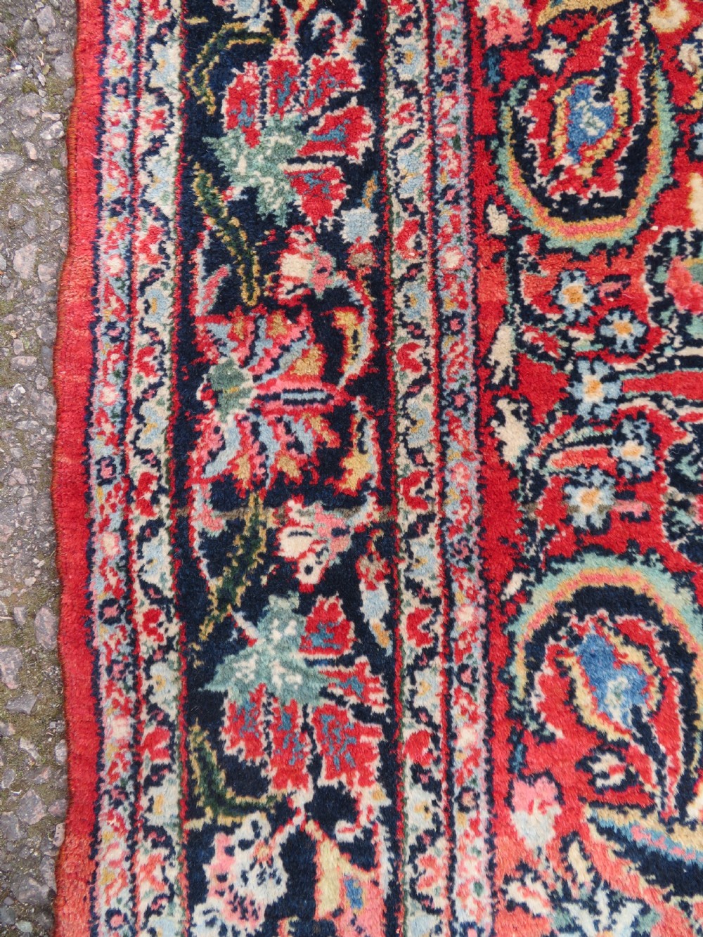 An antique hand-knotted Persian Sarouk wool rug featuring a red field with a central navy medallion and dense floral motifs within a dark border. View X