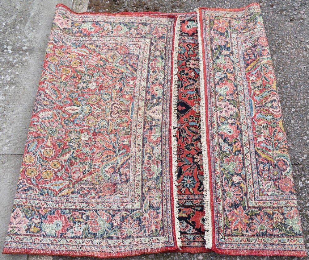 An antique hand-knotted Persian Sarouk wool rug featuring a red field with a central navy medallion and dense floral motifs within a dark border. View XIV