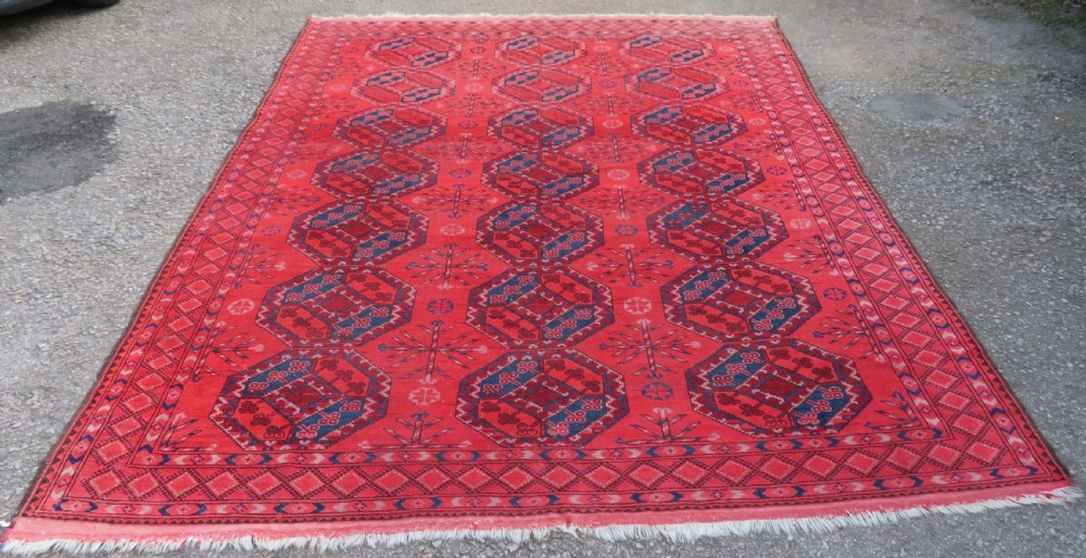 A large hand-knotted red wool Ersari carpet featuring repeating octagonal gul motifs and geometric border bands.
