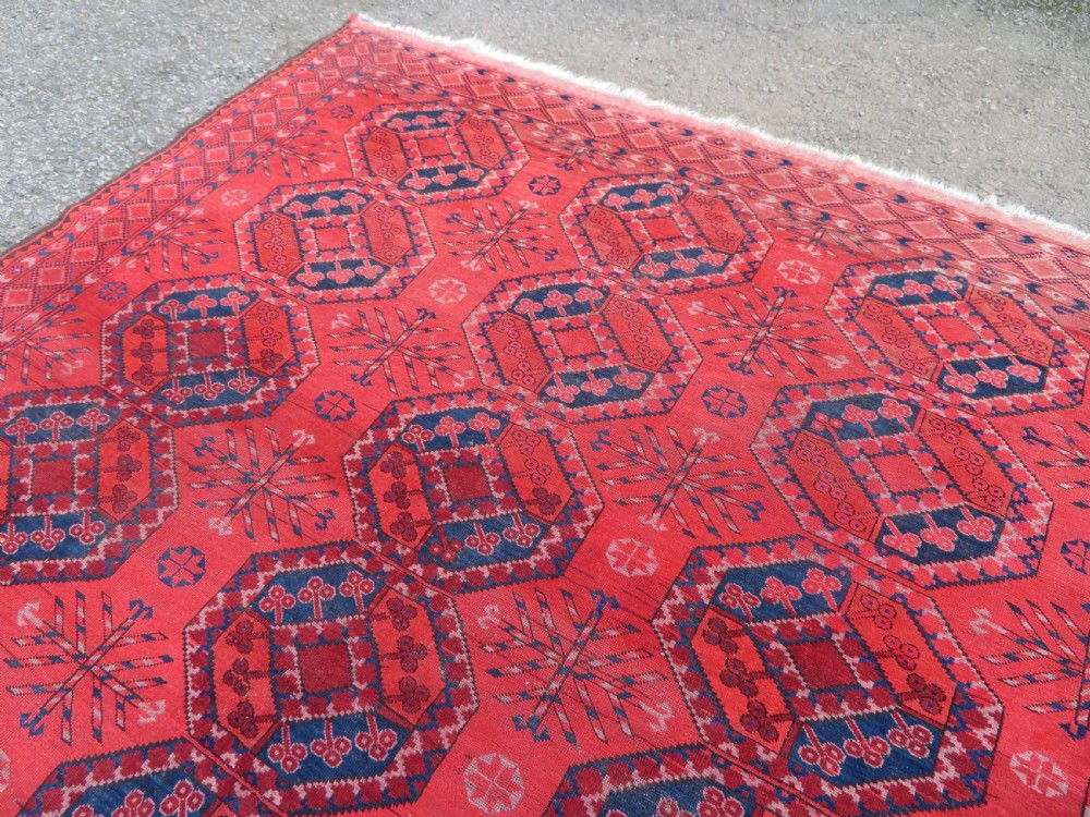A large hand-knotted red wool Ersari carpet featuring repeating octagonal gul motifs and geometric border bands. View VII