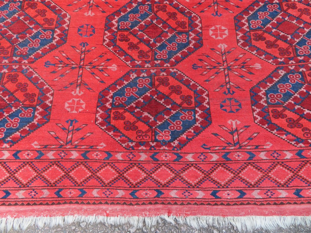 A large hand-knotted red wool Ersari carpet featuring repeating octagonal gul motifs and geometric border bands. View XXI