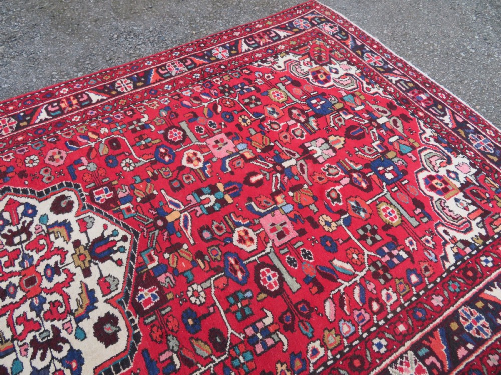 A long hand-knotted Persian Hamadan Kelleh carpet featuring a central cream medallion surrounded by geometric and floral motifs on a red field with multi-tiered borders. View VI