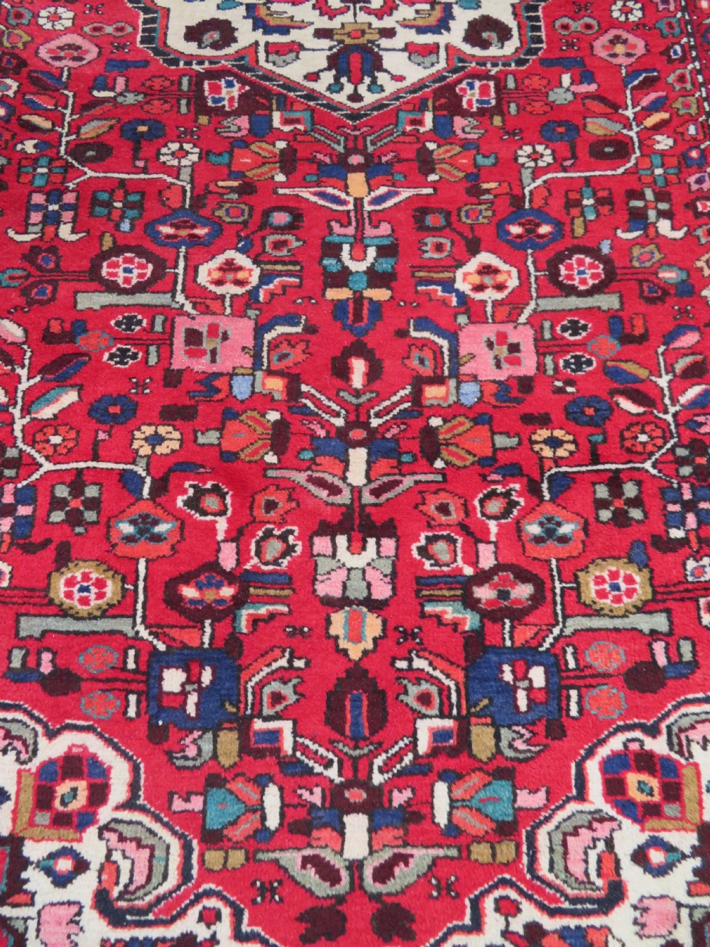A long hand-knotted Persian Hamadan Kelleh carpet featuring a central cream medallion surrounded by geometric and floral motifs on a red field with multi-tiered borders. View VII
