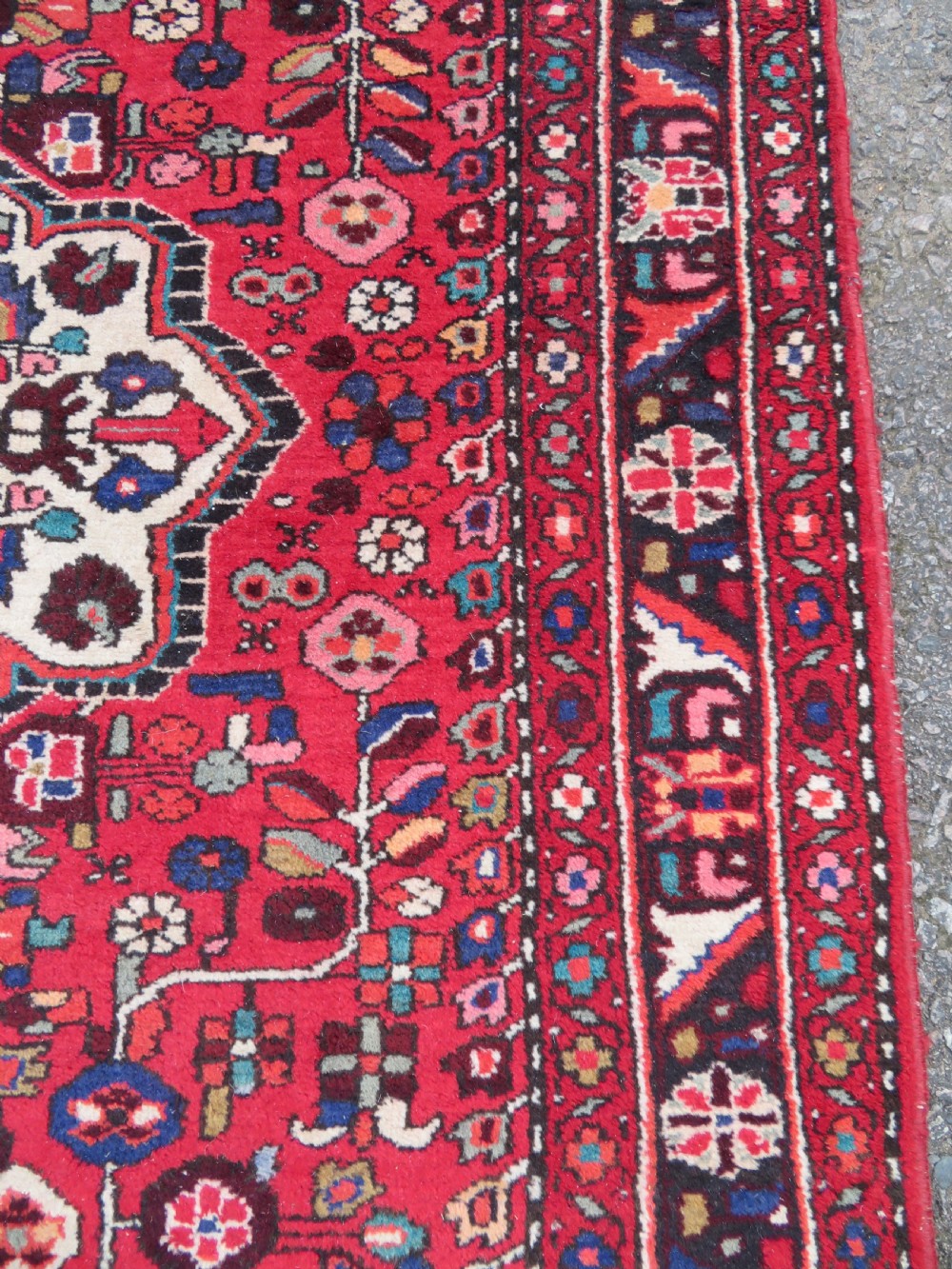 A long hand-knotted Persian Hamadan Kelleh carpet featuring a central cream medallion surrounded by geometric and floral motifs on a red field with multi-tiered borders. View X