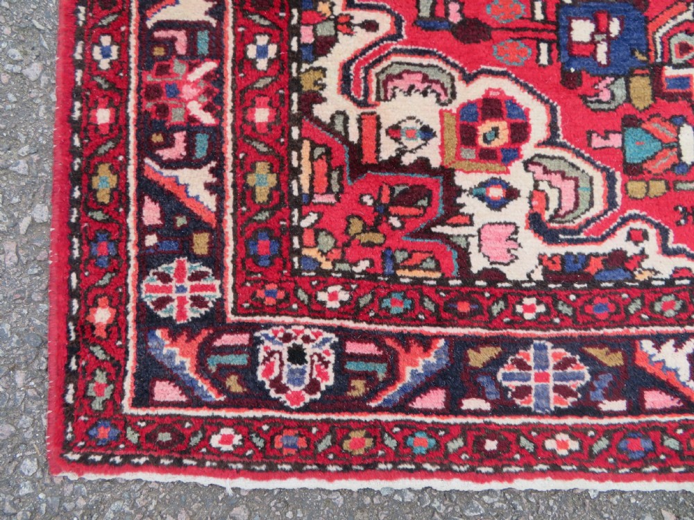 A long hand-knotted Persian Hamadan Kelleh carpet featuring a central cream medallion surrounded by geometric and floral motifs on a red field with multi-tiered borders. View XI