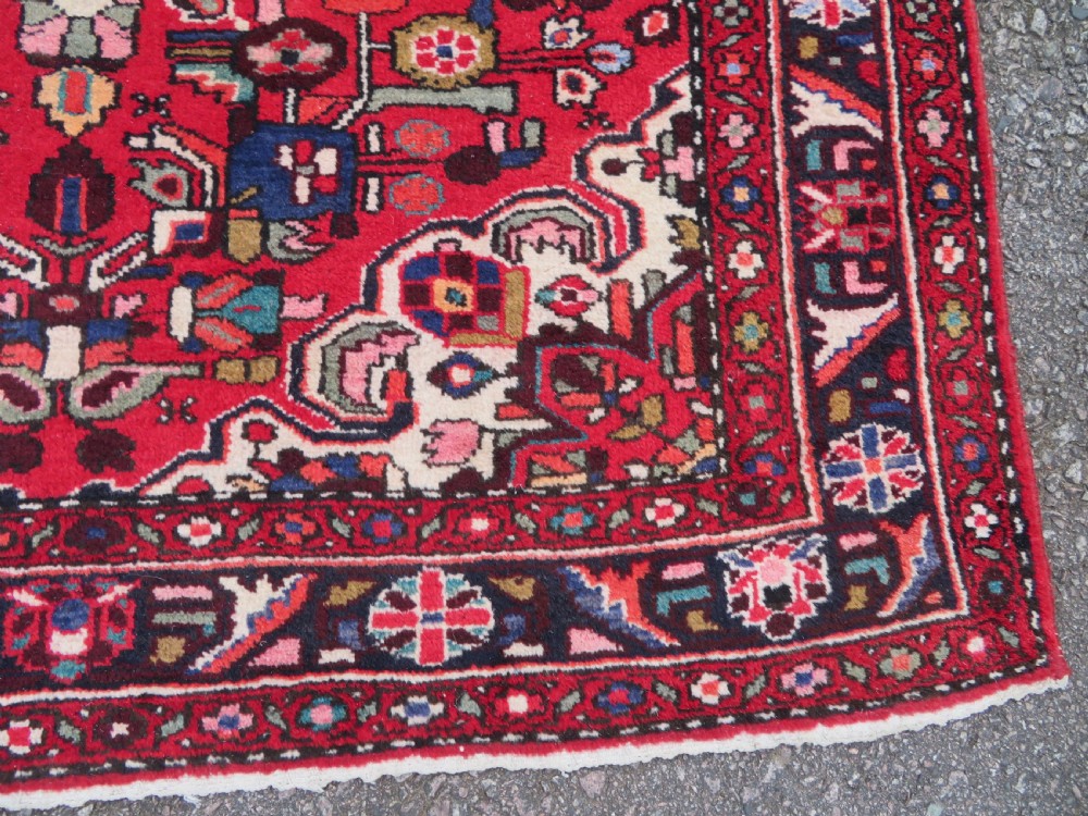 A long hand-knotted Persian Hamadan Kelleh carpet featuring a central cream medallion surrounded by geometric and floral motifs on a red field with multi-tiered borders. View XII
