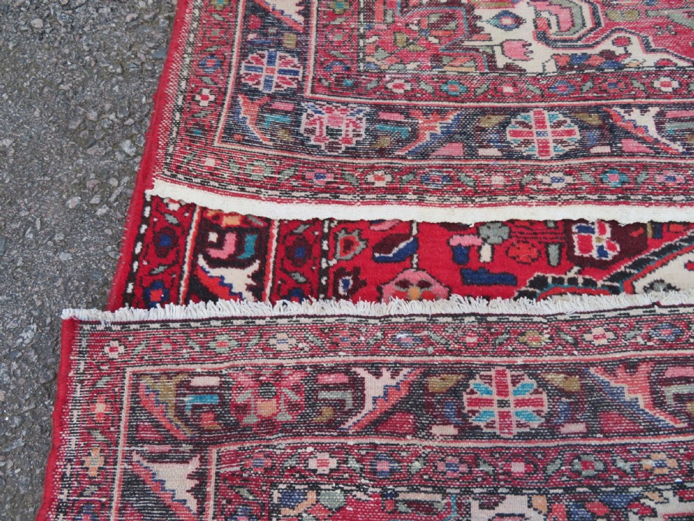 A long hand-knotted Persian Hamadan Kelleh carpet featuring a central cream medallion surrounded by geometric and floral motifs on a red field with multi-tiered borders. View XV