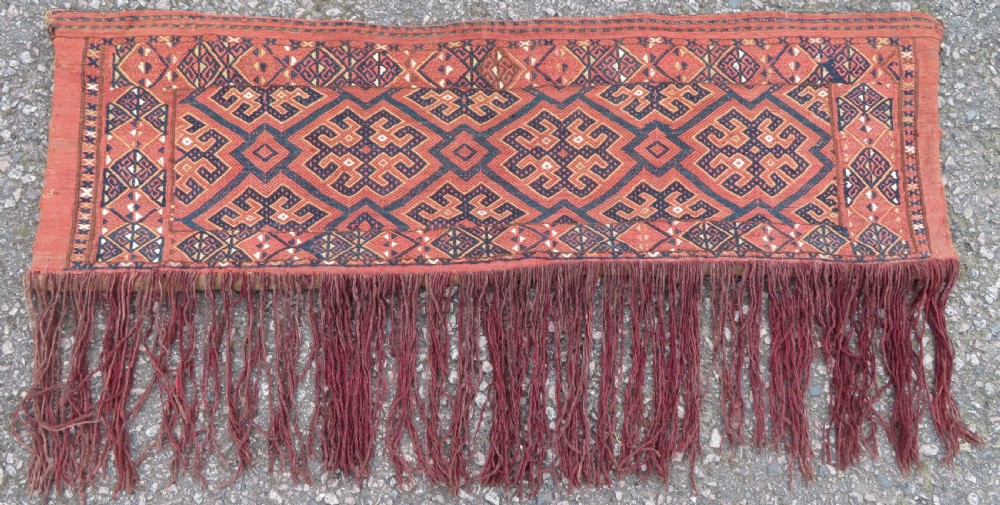 An Ersari Turkmen flatweave wool torba featuring geometric motifs in terracotta red, navy, and ivory, complete with a long fringed lower border.