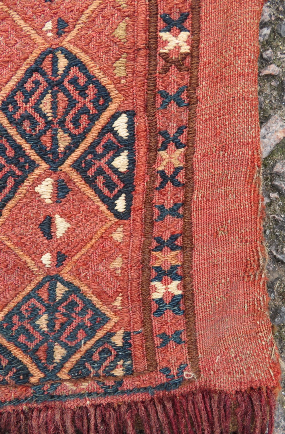 An Ersari Turkmen flatweave wool torba featuring geometric motifs in terracotta red, navy, and ivory, complete with a long fringed lower border. View V