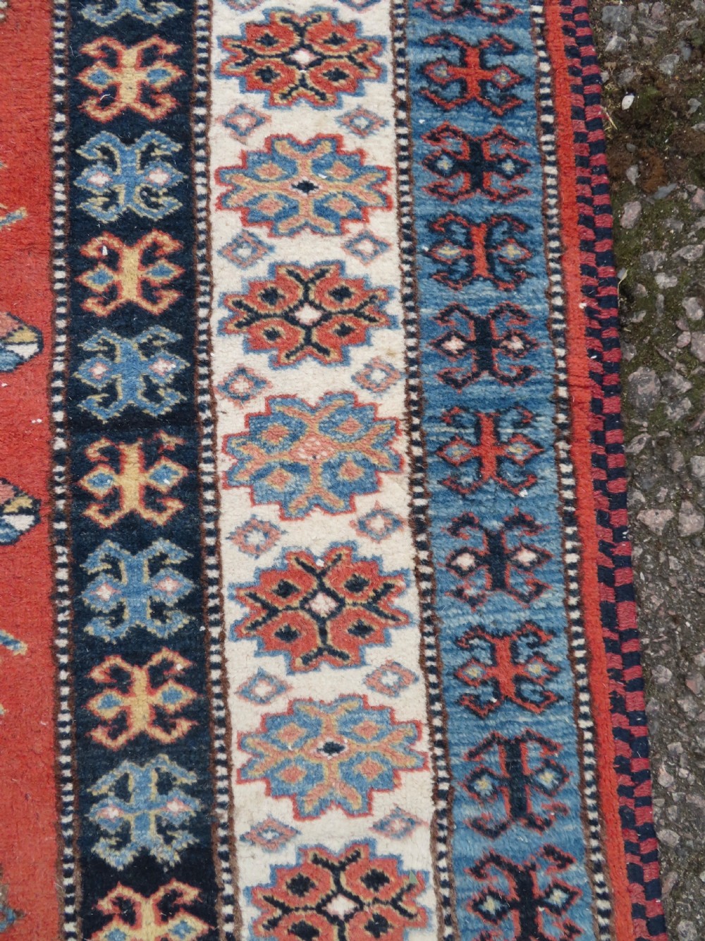 A handwoven rectangular wool rug featuring a central navy blue stepped medallion and a terracotta field decorated with peacock and animal motifs. View XI
