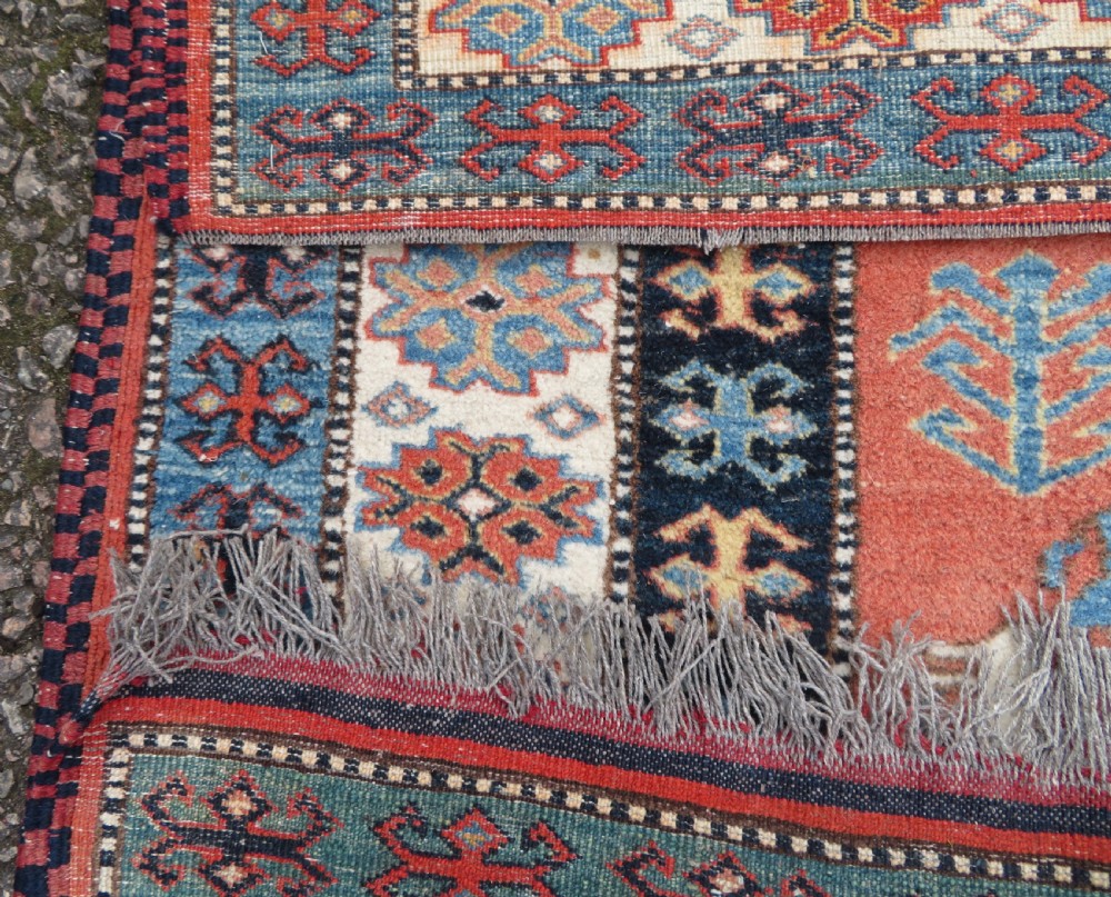 A handwoven rectangular wool rug featuring a central navy blue stepped medallion and a terracotta field decorated with peacock and animal motifs. View XVIII