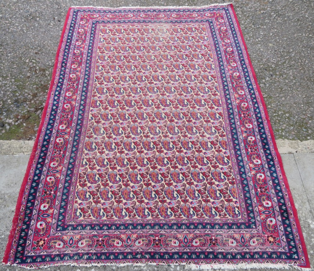 An antique Persian Meshed Doroksh wool rug featuring a repeating all-over boteh pattern on a cream field within multi-banded crimson and navy borders. View II