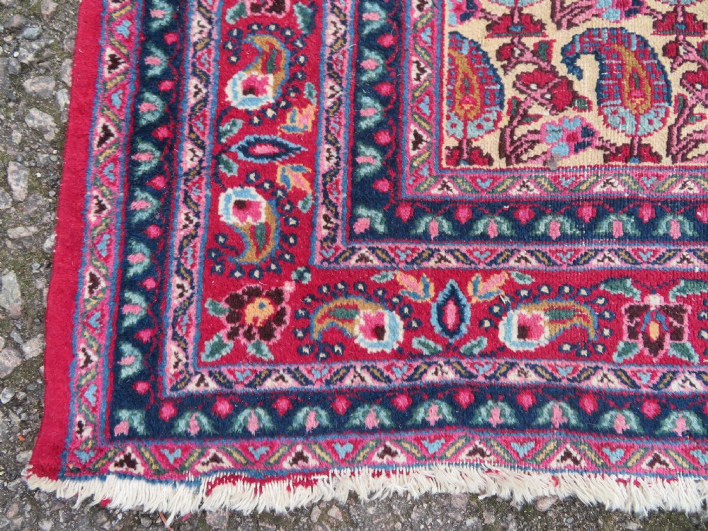 An antique Persian Meshed Doroksh wool rug featuring a repeating all-over boteh pattern on a cream field within multi-banded crimson and navy borders. View VII