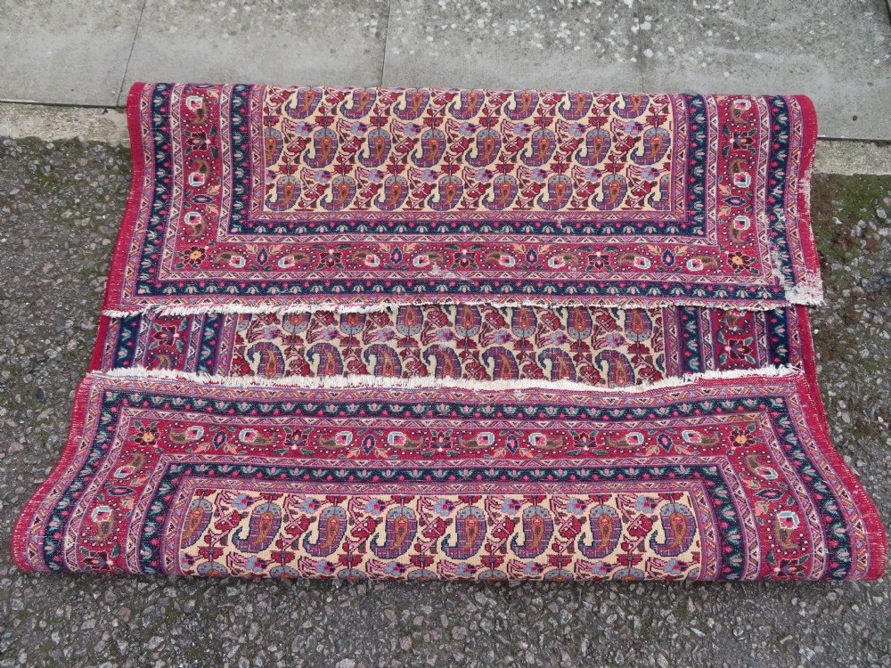 An antique Persian Meshed Doroksh wool rug featuring a repeating all-over boteh pattern on a cream field within multi-banded crimson and navy borders. View XIV