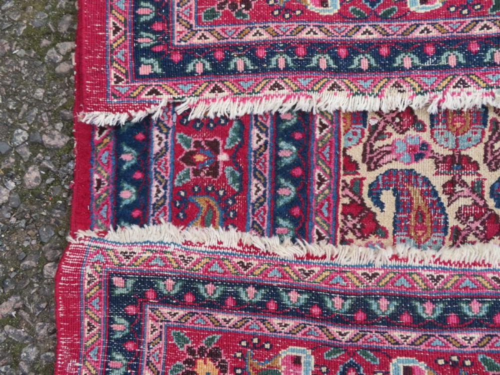 An antique Persian Meshed Doroksh wool rug featuring a repeating all-over boteh pattern on a cream field within multi-banded crimson and navy borders. View XVI