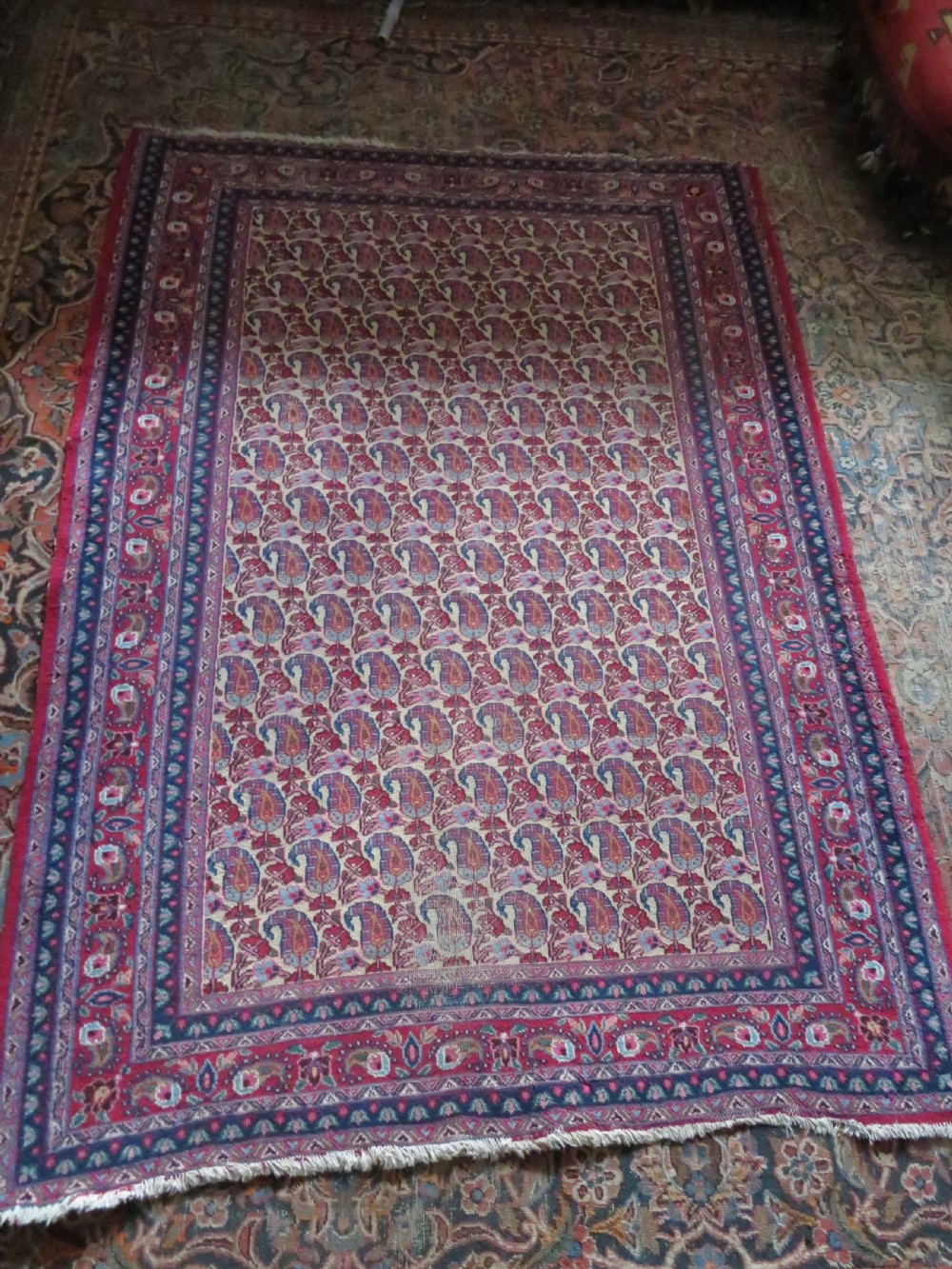An antique Persian Meshed Doroksh wool rug featuring a repeating all-over boteh pattern on a cream field within multi-banded crimson and navy borders. View XVIII