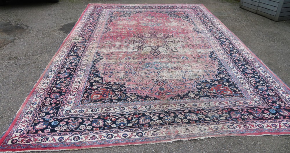 A large hand-knotted Persian Sarouk wool carpet featuring a distressed rose red field, central floral medallion, and deep navy blue floral borders. View II