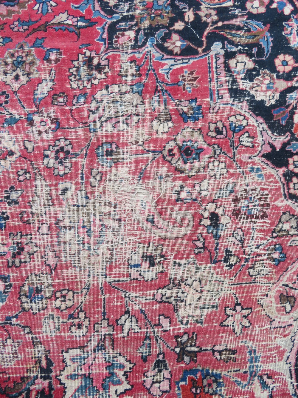 A large hand-knotted Persian Sarouk wool carpet featuring a distressed rose red field, central floral medallion, and deep navy blue floral borders. View XIV