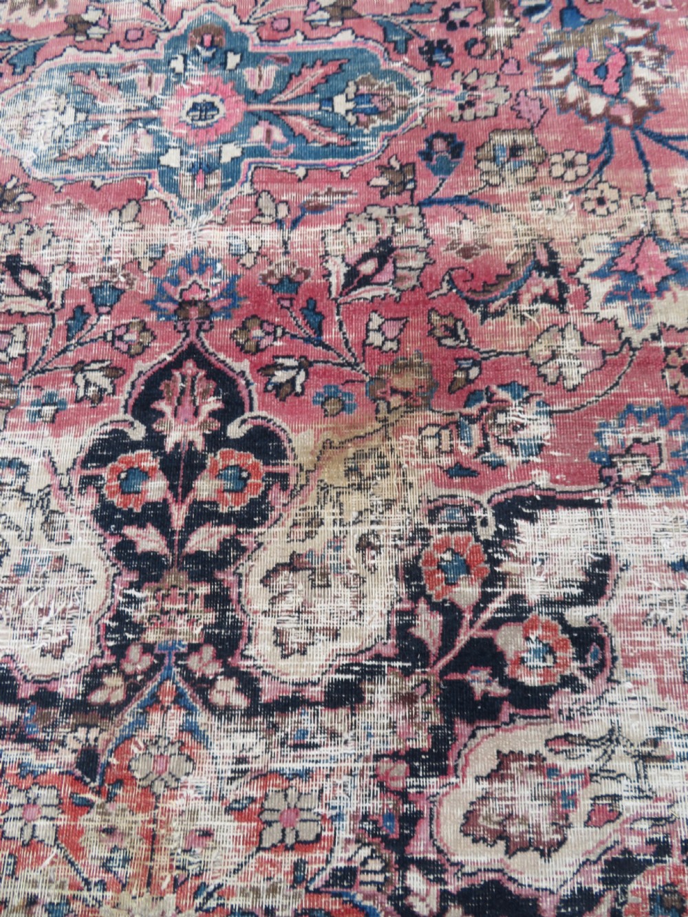 A large hand-knotted Persian Sarouk wool carpet featuring a distressed rose red field, central floral medallion, and deep navy blue floral borders. View XXIII