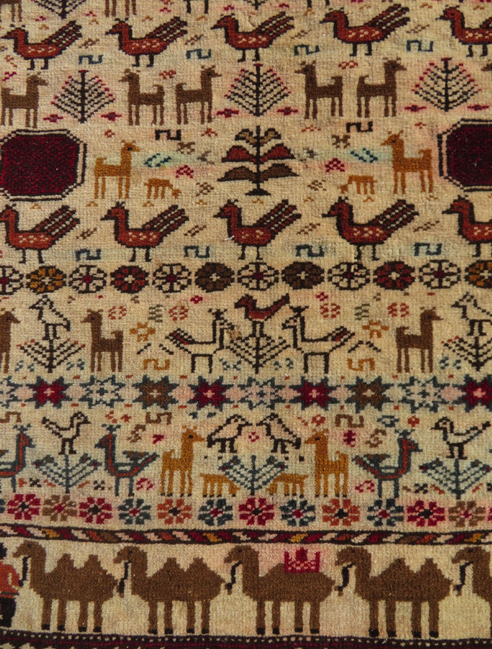 Hand-knotted wool Baluch prayer rug with a cream field featuring stylized camels, birds, hand symbols, and a mihrab top border. View III