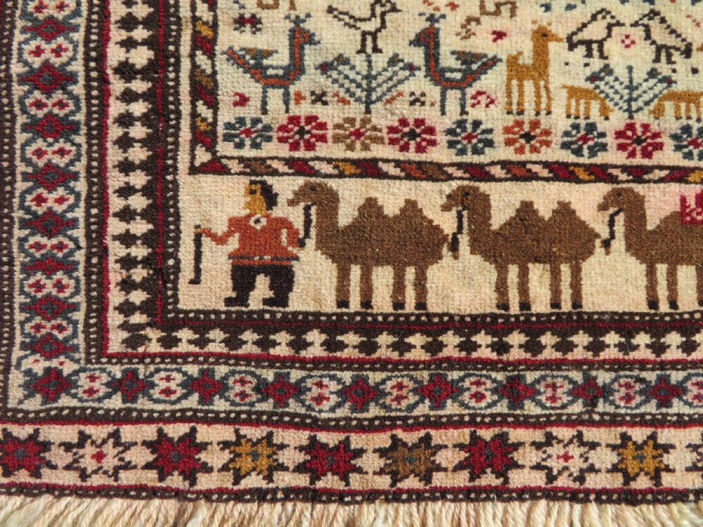 Hand-knotted wool Baluch prayer rug with a cream field featuring stylized camels, birds, hand symbols, and a mihrab top border. View IV
