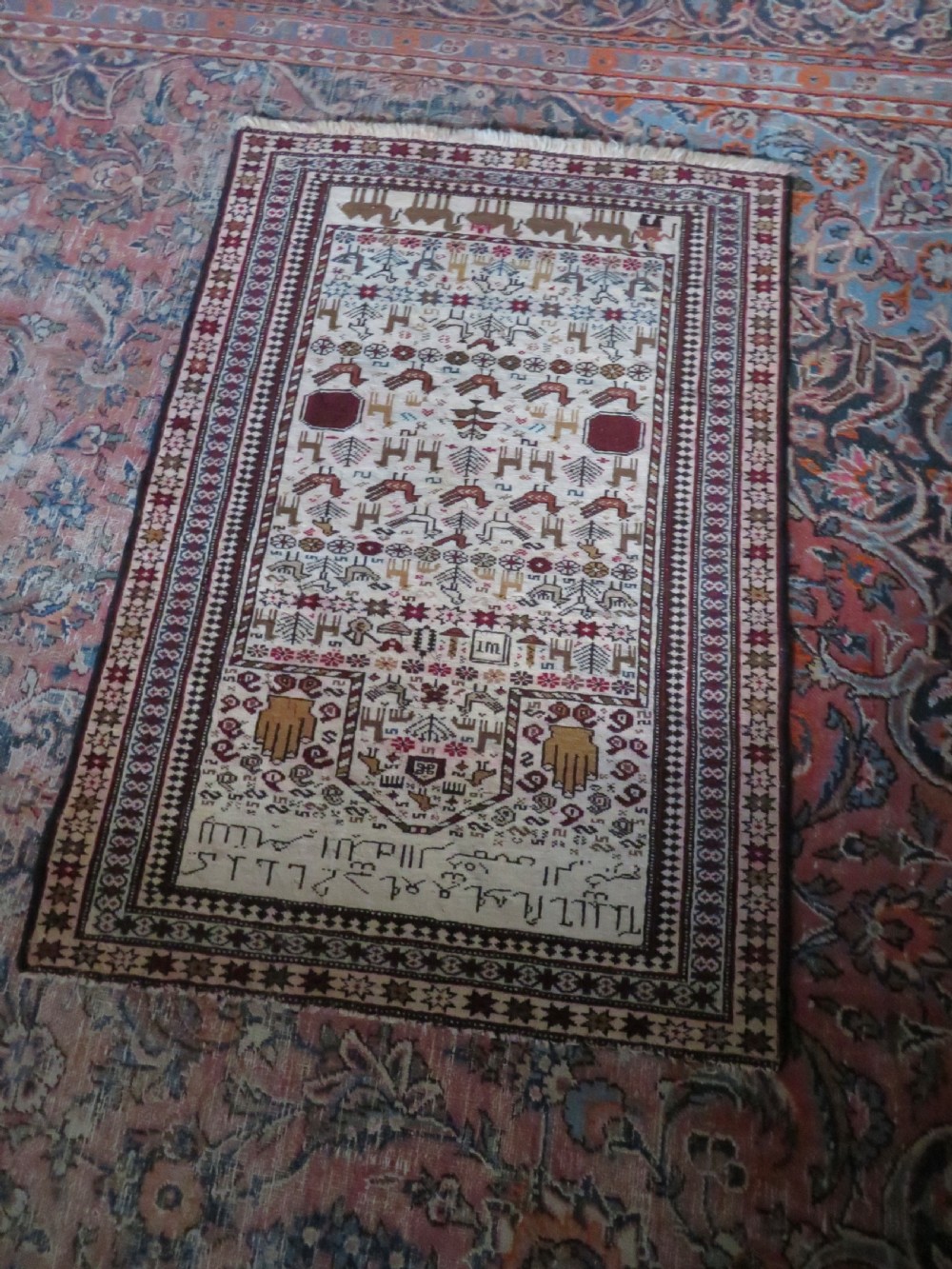 Hand-knotted wool Baluch prayer rug with a cream field featuring stylized camels, birds, hand symbols, and a mihrab top border. View XVI
