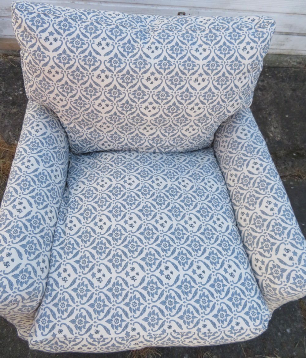 A deeply cushioned upholstered armchair featuring blue and cream patterned fabric, padded arms, and dark tapered wooden legs on brass castors. View VIII