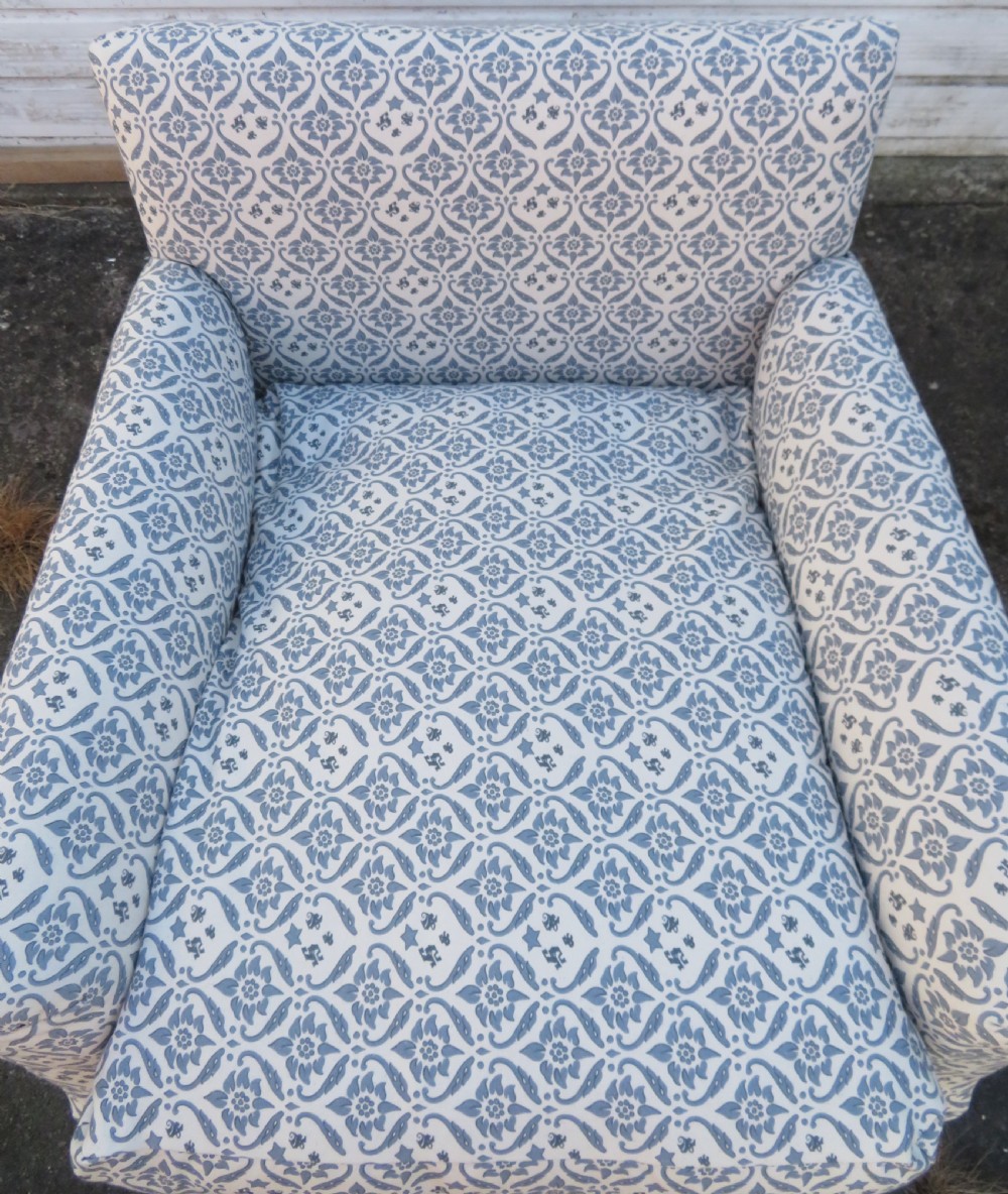 A deeply cushioned upholstered armchair featuring blue and cream patterned fabric, padded arms, and dark tapered wooden legs on brass castors. View IX