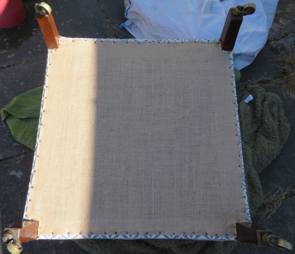 A deeply cushioned upholstered armchair featuring blue and cream patterned fabric, padded arms, and dark tapered wooden legs on brass castors. View XVIII