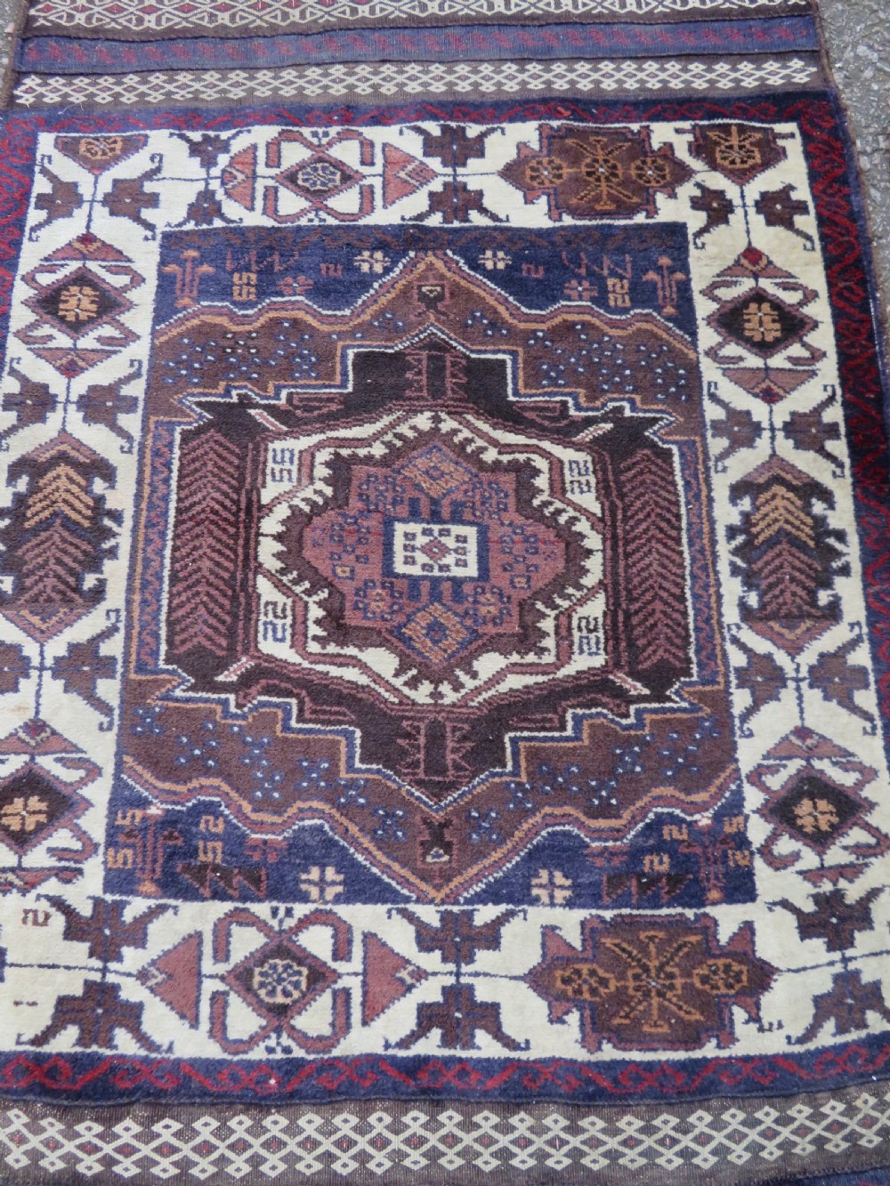A pair of hand-woven tribal wool rugs featuring geometric medallions in tones of red, blue, brown, and cream with fringed edges. View IV