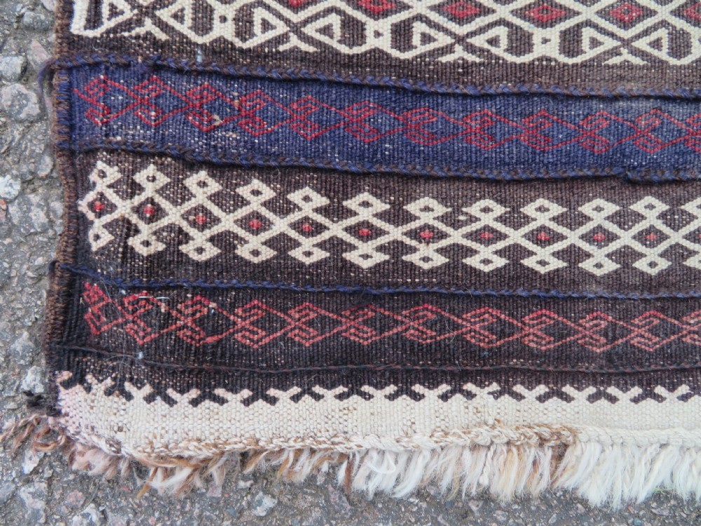 A pair of hand-woven tribal wool rugs featuring geometric medallions in tones of red, blue, brown, and cream with fringed edges. View V