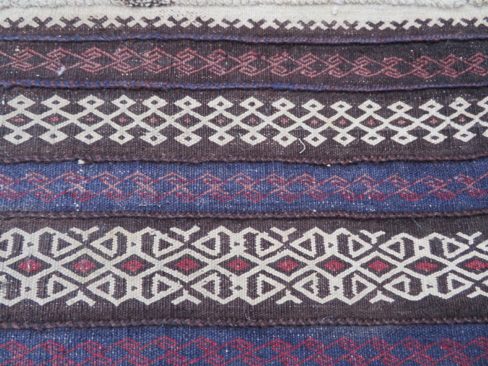 A pair of hand-woven tribal wool rugs featuring geometric medallions in tones of red, blue, brown, and cream with fringed edges. View VI