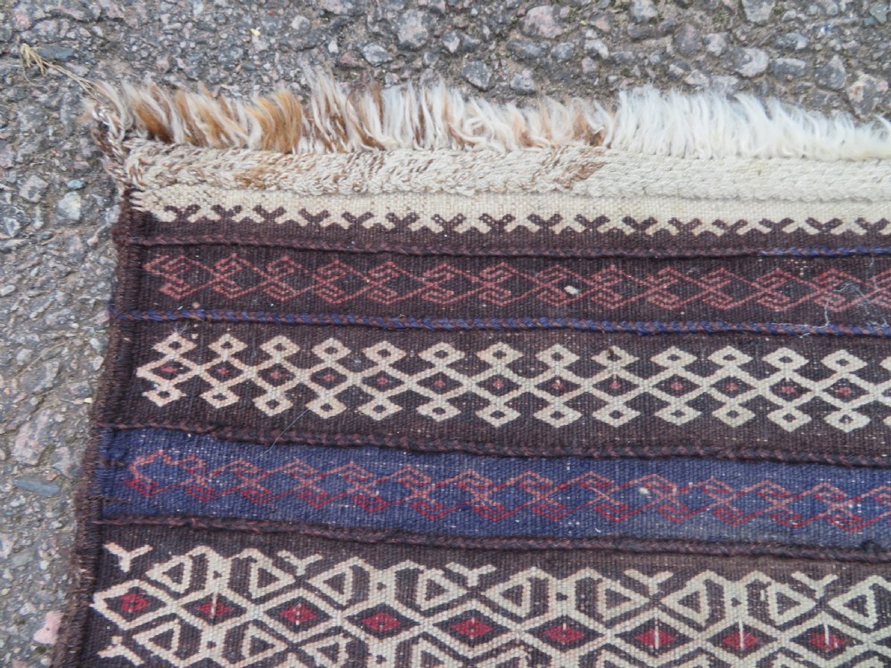 A pair of hand-woven tribal wool rugs featuring geometric medallions in tones of red, blue, brown, and cream with fringed edges. View VII