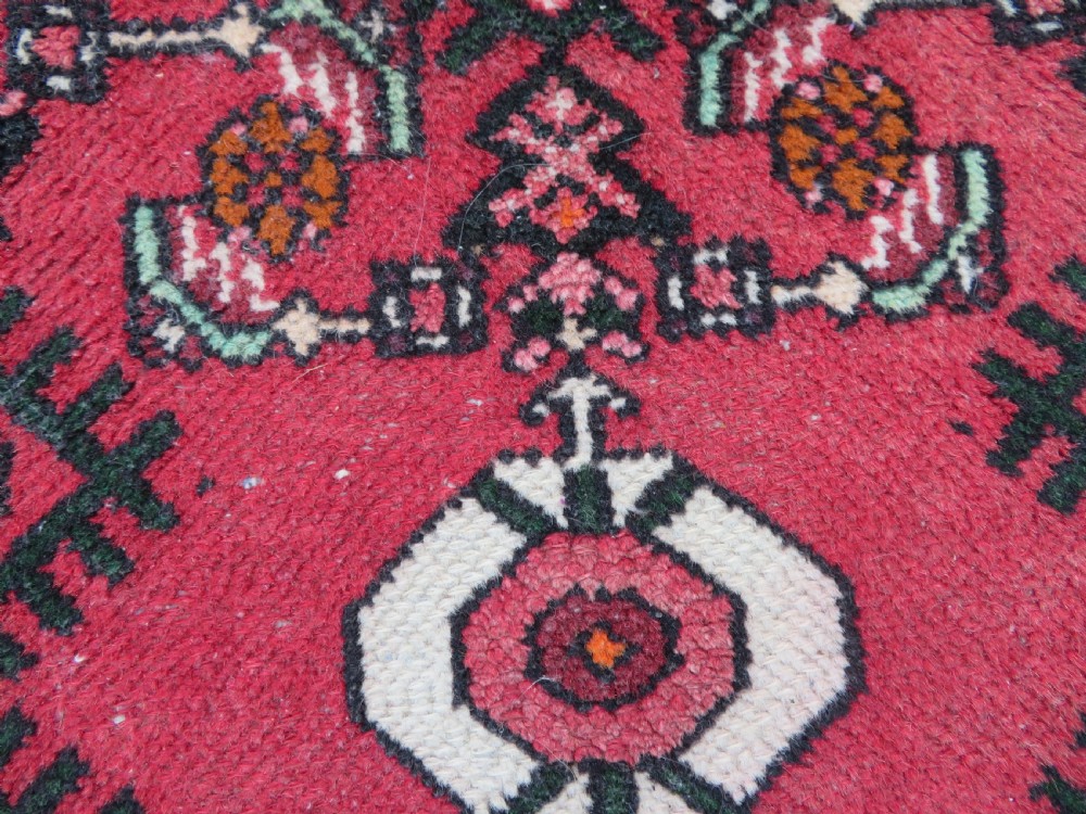 A pair of hand-woven tribal wool rugs featuring geometric medallions in tones of red, blue, brown, and cream with fringed edges. View VIII