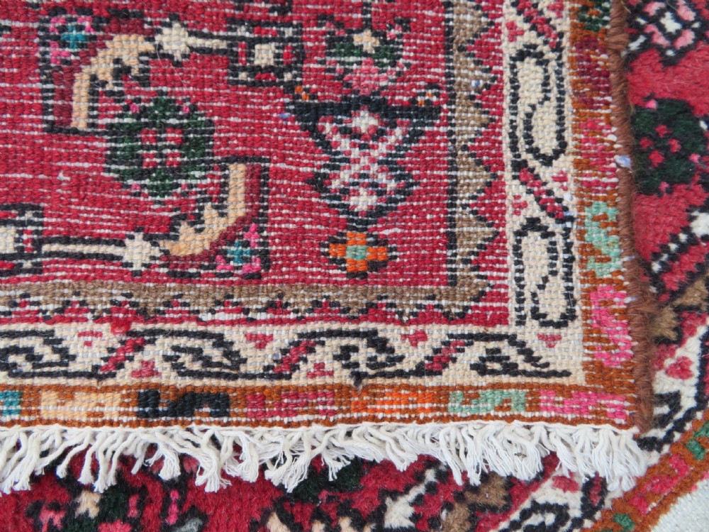 A pair of hand-woven tribal wool rugs featuring geometric medallions in tones of red, blue, brown, and cream with fringed edges. View XI