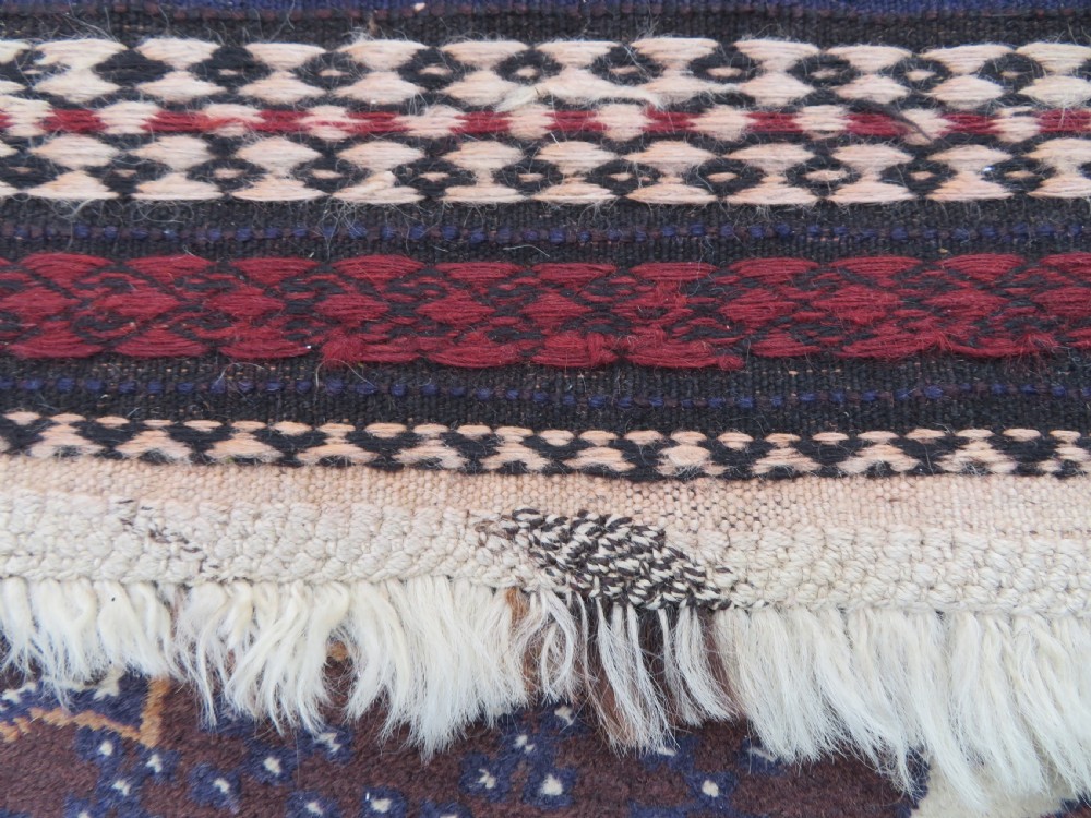 A pair of hand-woven tribal wool rugs featuring geometric medallions in tones of red, blue, brown, and cream with fringed edges. View XII