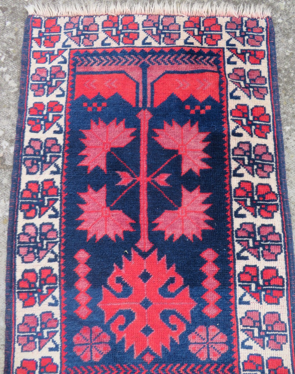 A long, narrow hand-knotted Turkish Yagjibedir runner rug featuring geometric tribal motifs in deep red against a dark navy blue background with a patterned ivory border. View III
