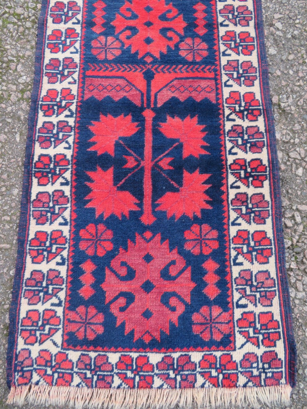 A long, narrow hand-knotted Turkish Yagjibedir runner rug featuring geometric tribal motifs in deep red against a dark navy blue background with a patterned ivory border. View IV