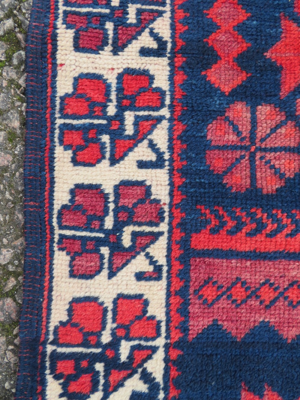 A long, narrow hand-knotted Turkish Yagjibedir runner rug featuring geometric tribal motifs in deep red against a dark navy blue background with a patterned ivory border. View V