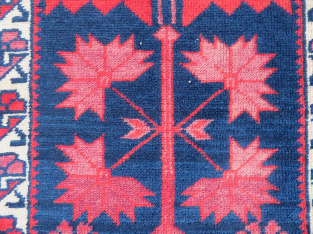 A long, narrow hand-knotted Turkish Yagjibedir runner rug featuring geometric tribal motifs in deep red against a dark navy blue background with a patterned ivory border. View VII